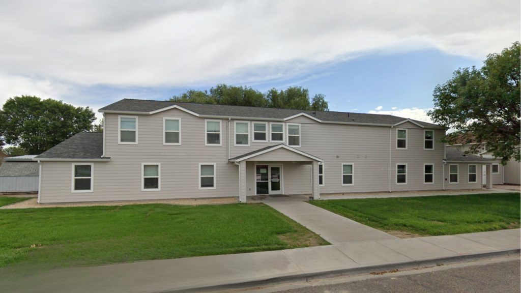 Two-story beige rehab center building with front entrance and lawn