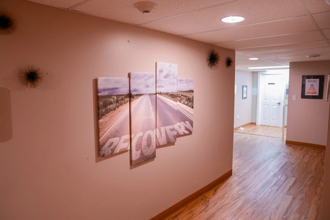 Hallway with recovery wall art and wood flooring