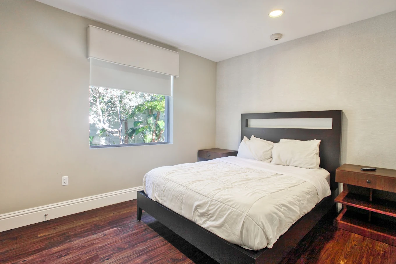 Private room with large bed, window, and hardwood floors