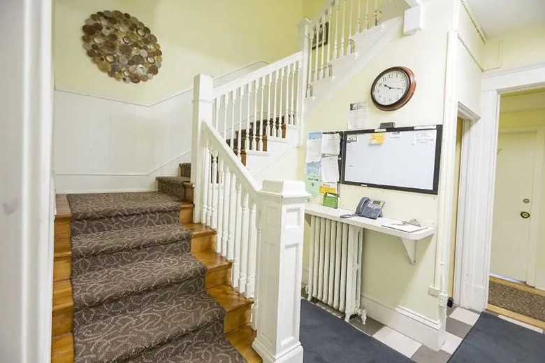 Carpeted staircase near reception desk and wall clock in hallway