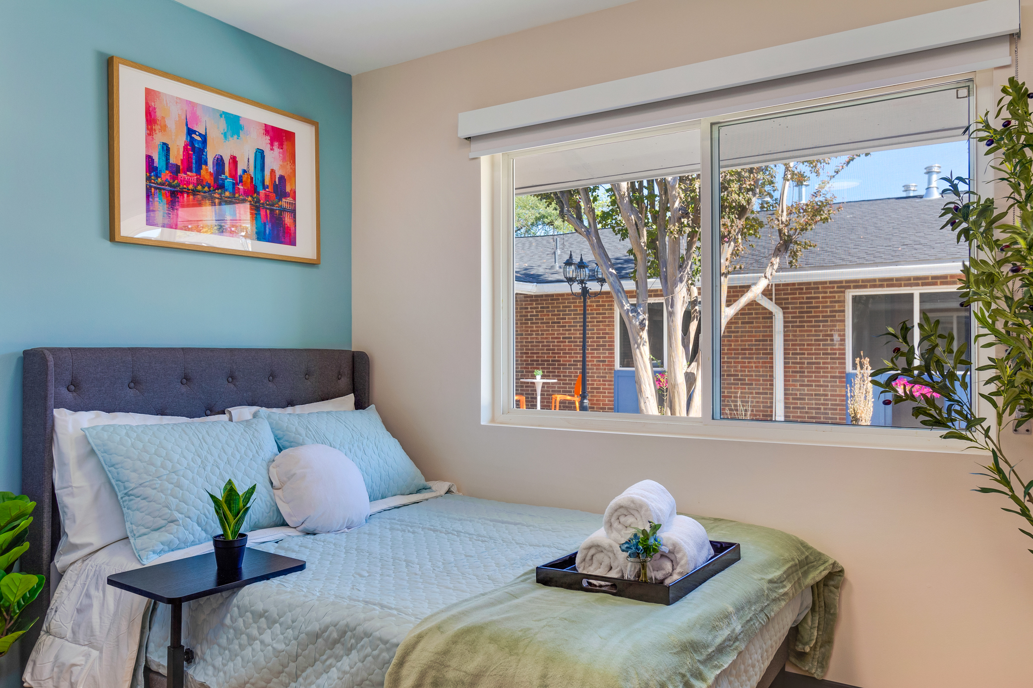 Bedroom with a bed, framed artwork, and a large window