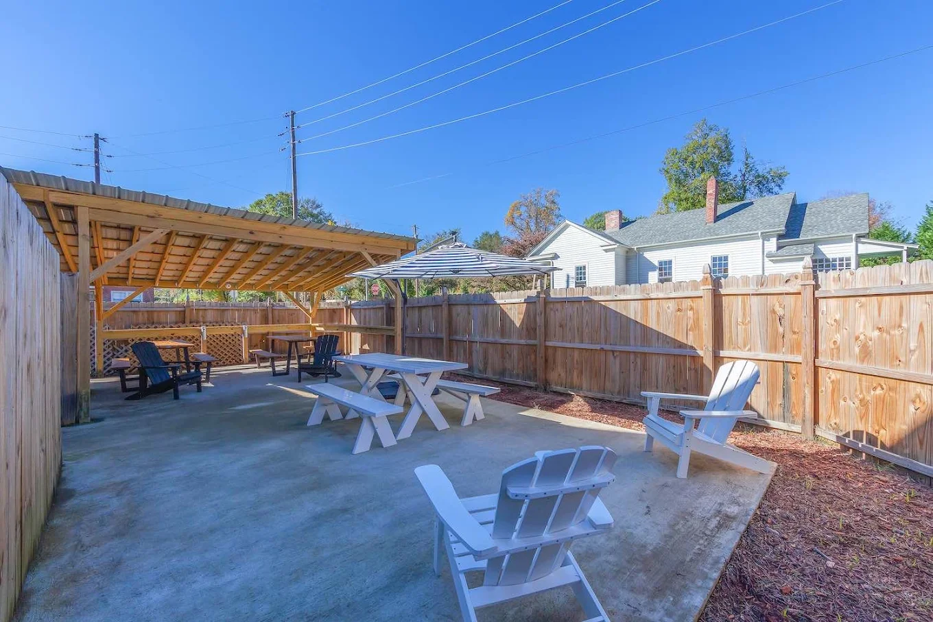 Fenced outdoor patio with covered seating and picnic tables