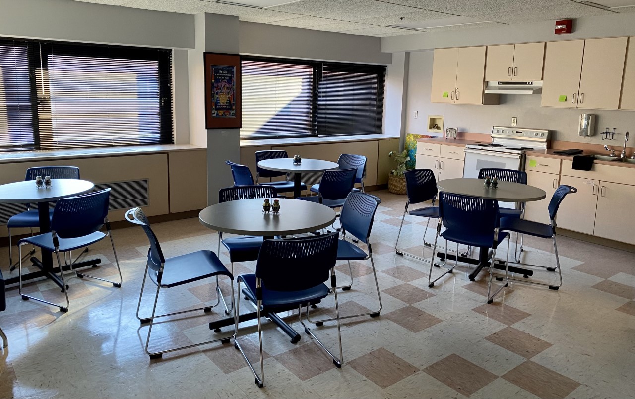 Bright dining area with round tables and kitchen space