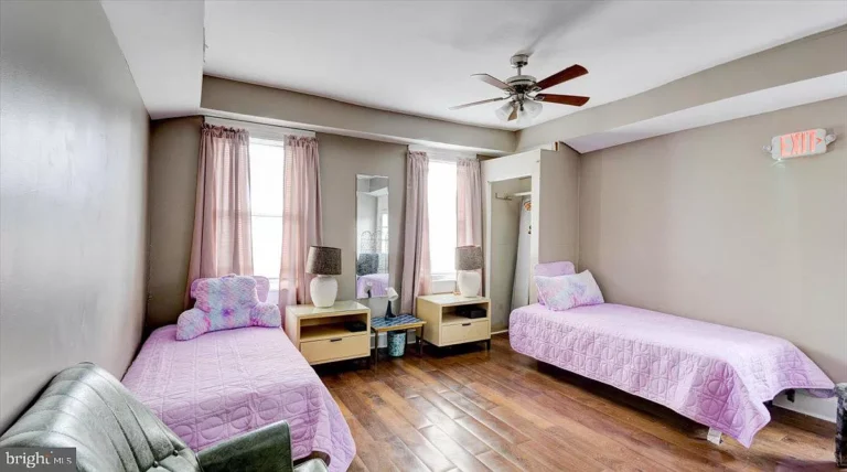 Shared bedroom with twin beds, pink bedding, and hardwood floors