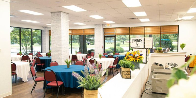 Bright and cheerful dining area with round tables, vibrant floral centerpieces, large windows with scenic views.