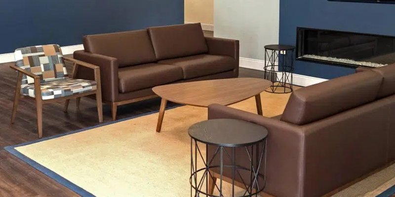 A stylish lounge area featuring brown leather sofas, a modern chair, a fireplace, and framed artwork on a deep blue accent wall.