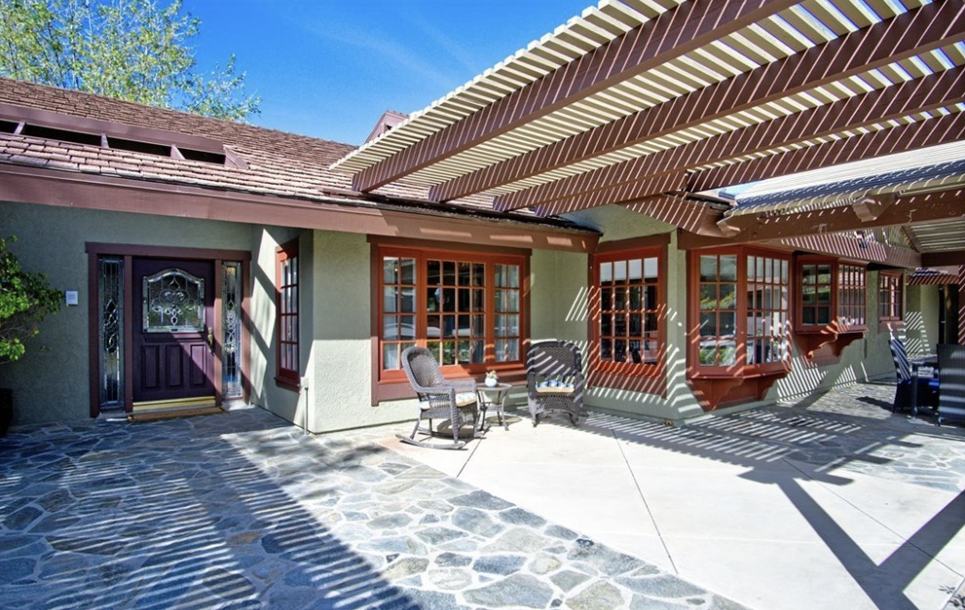 Entrance with a stone patio and pergola.