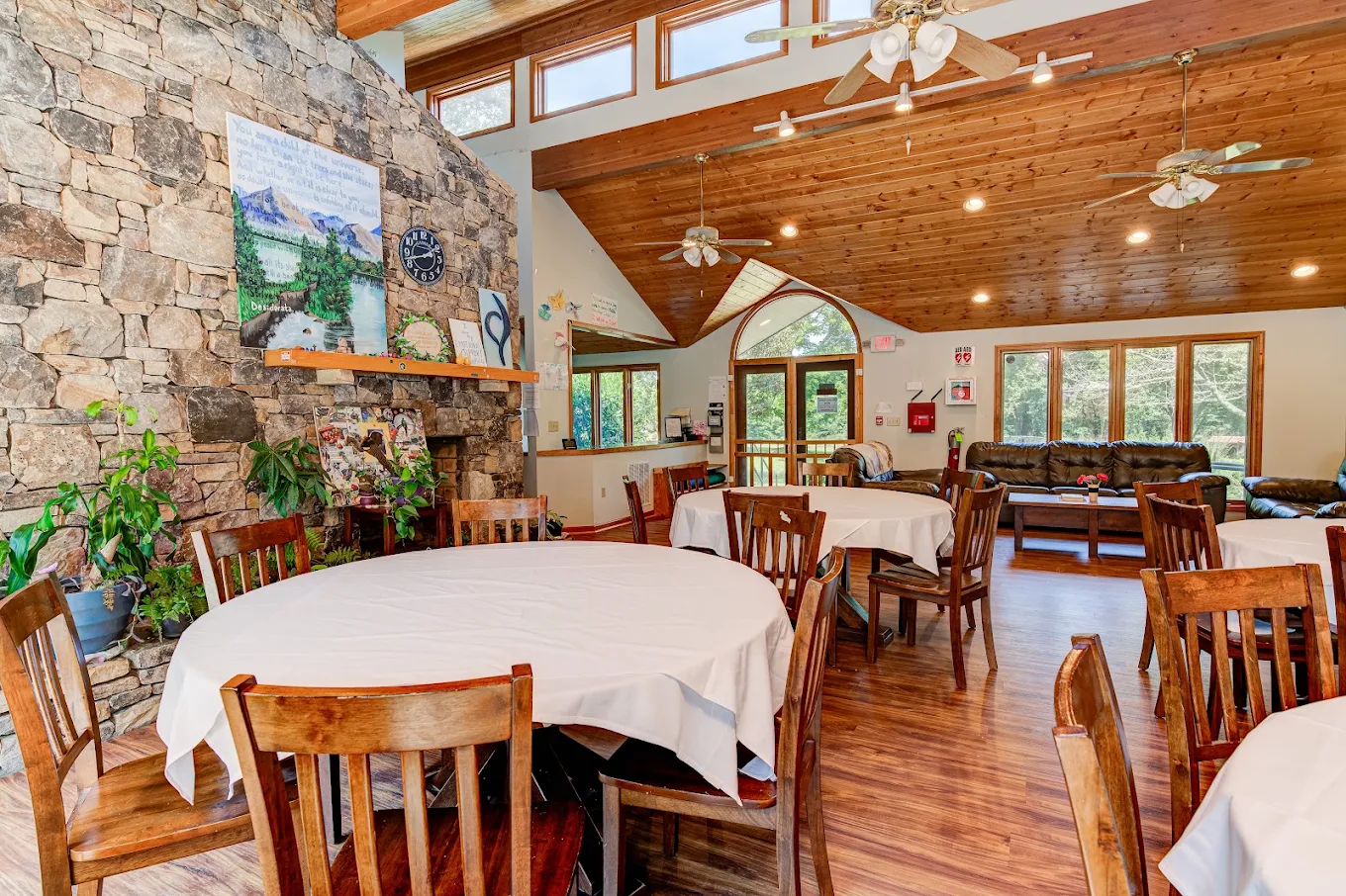 Communal dining room with round tables and stone fireplace