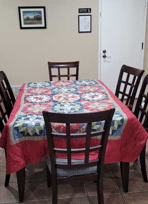 Dining table with patterned cloth and wooden chairs