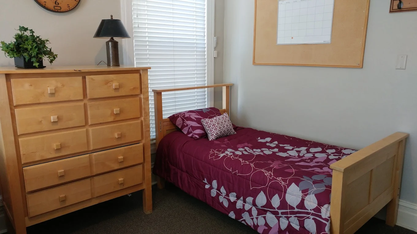 Single bed with wooden frame and dresser in private bedroom