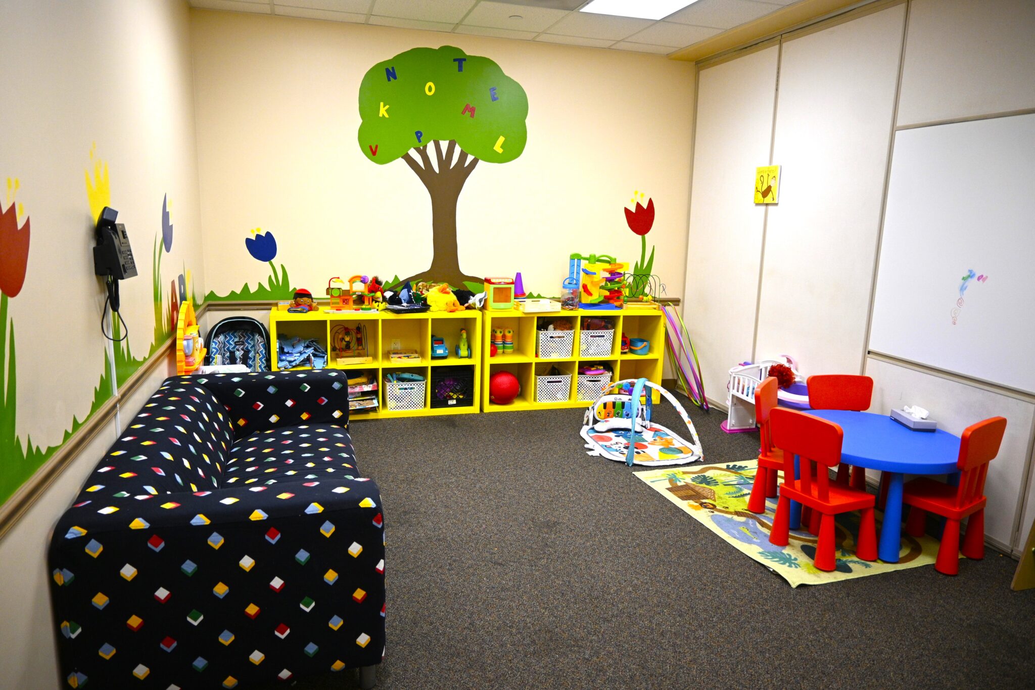 Colorful children’s visitation room with play mats and bookshelves