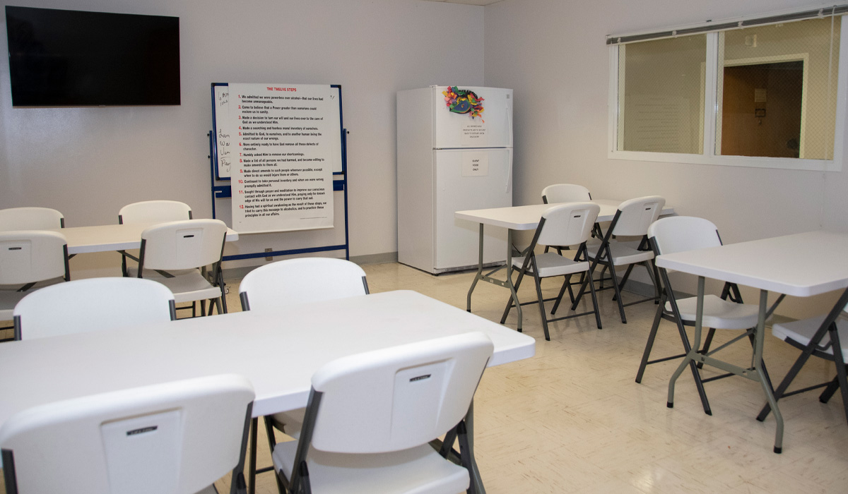 Dining room with tables, chairs, and a refrigerator.
