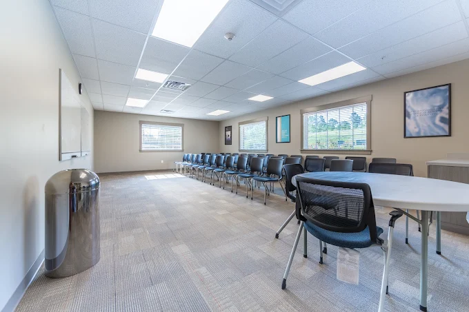 Meeting room with chairs arranged along the walls and large windows