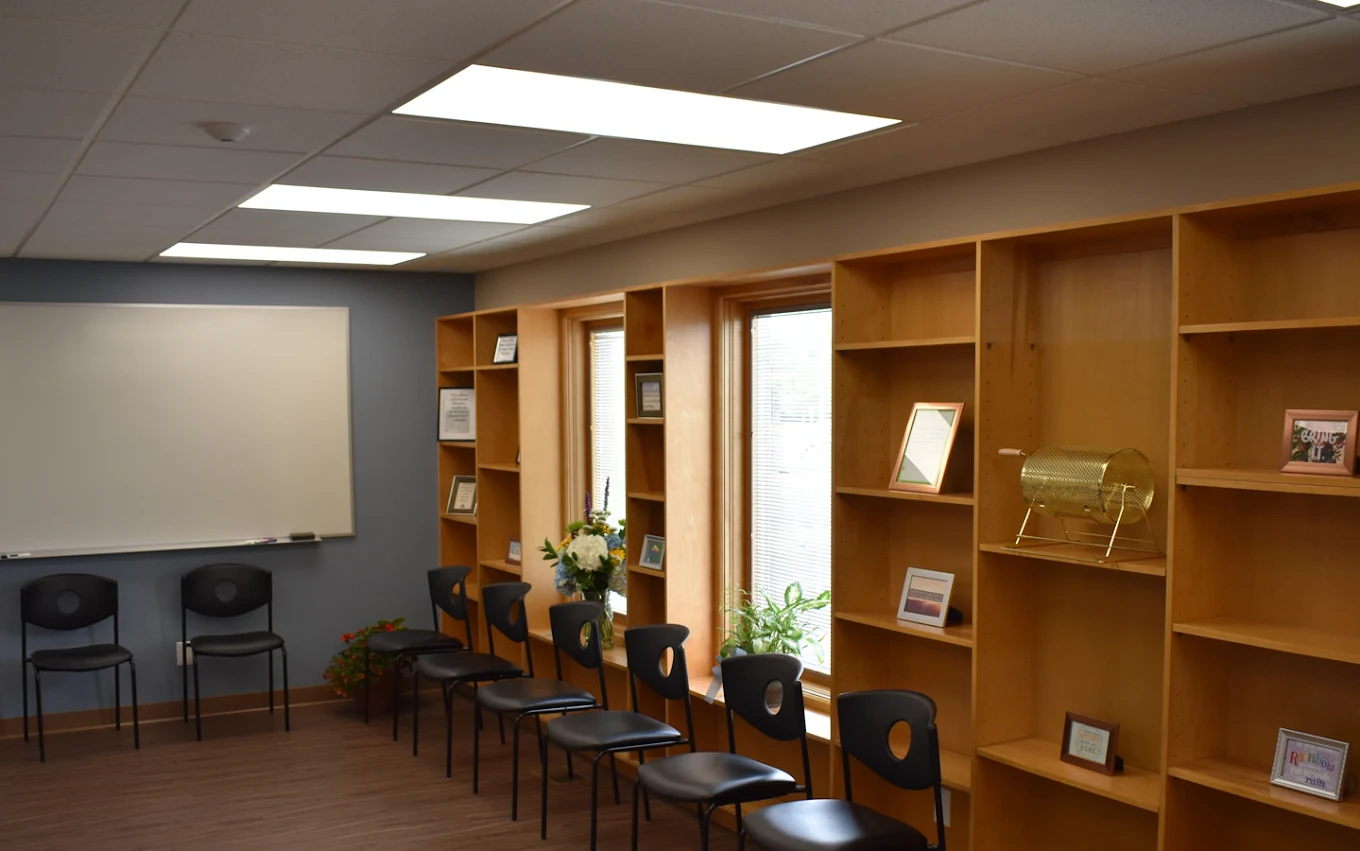 BrightView Health group room with rows of chairs, built-in wooden shelving, windows, and whiteboard