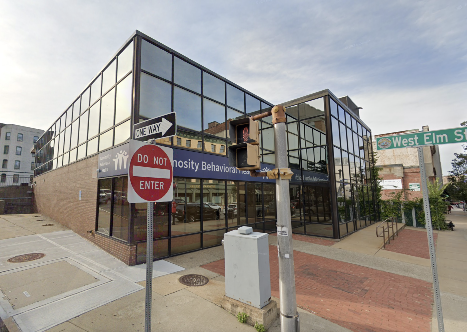A corner view of a contemporary behavioral health building with a clean, glass-fronted exterior, located at a busy intersection.