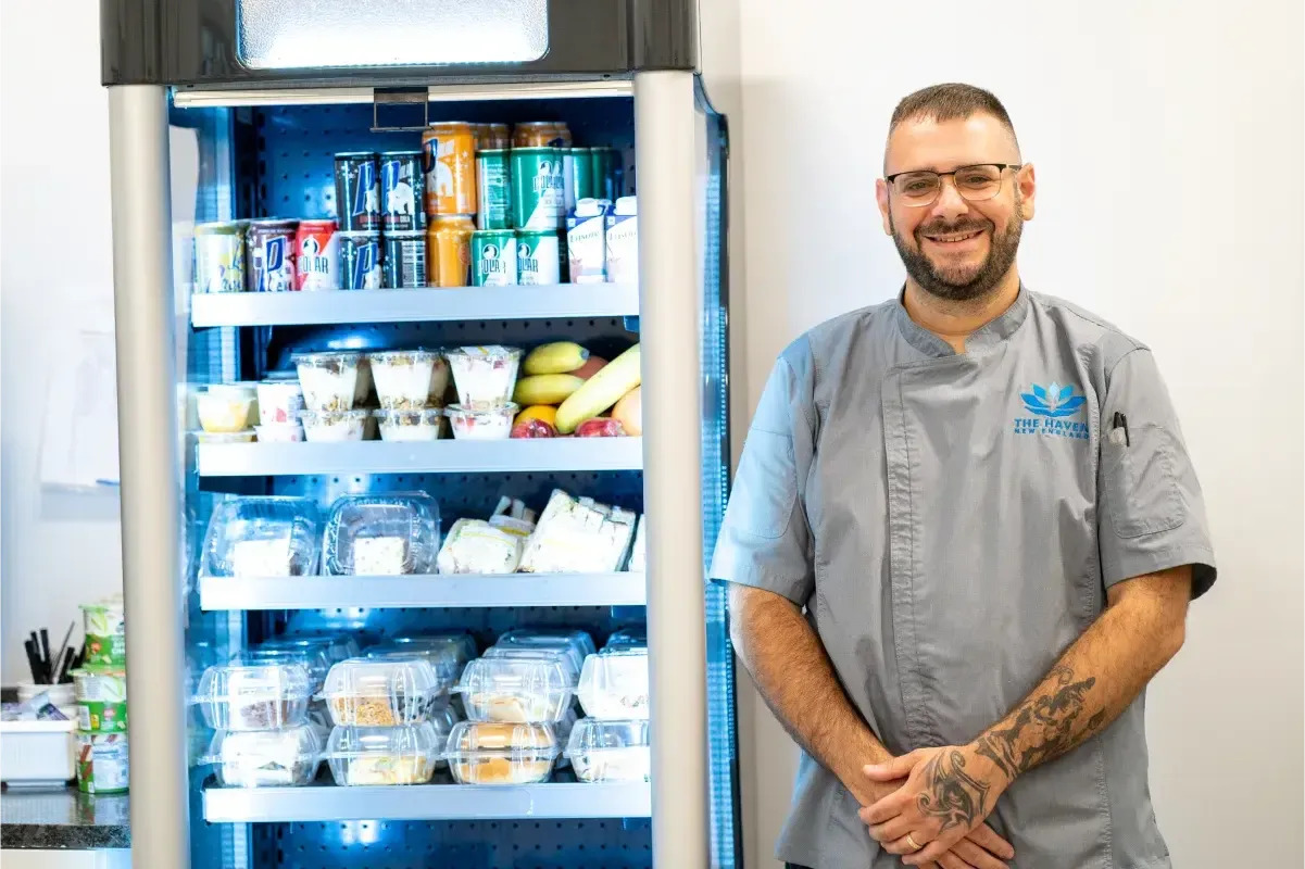 Chef standing beside a cooler of prepared meals.