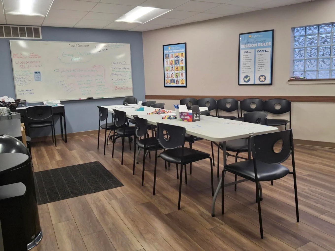 Group therapy room with tables, chairs, and whiteboard