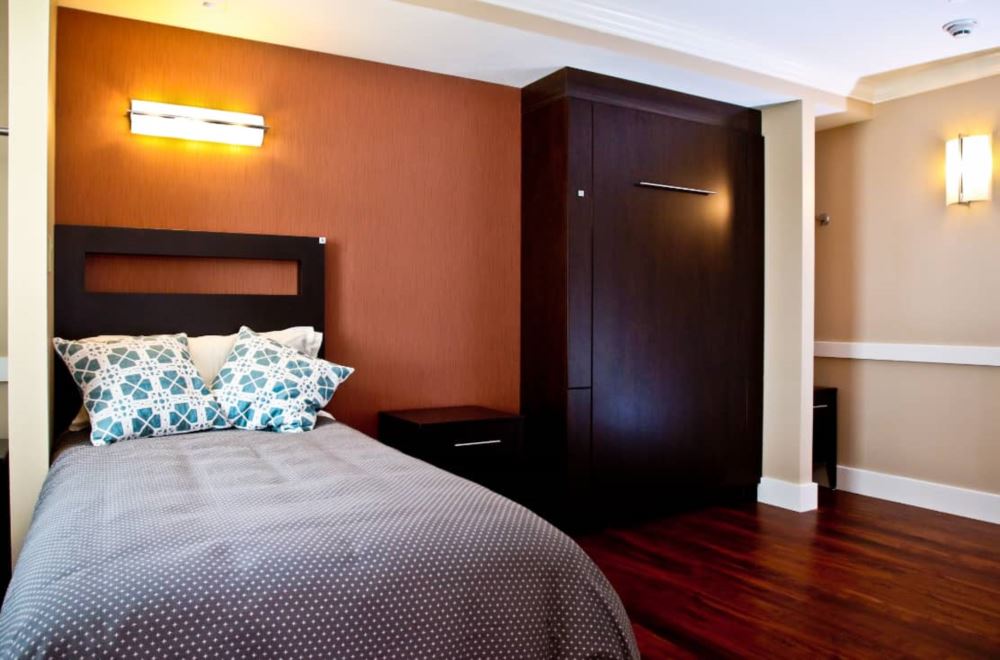 Single bed with dark wood furnishings and warm lighting