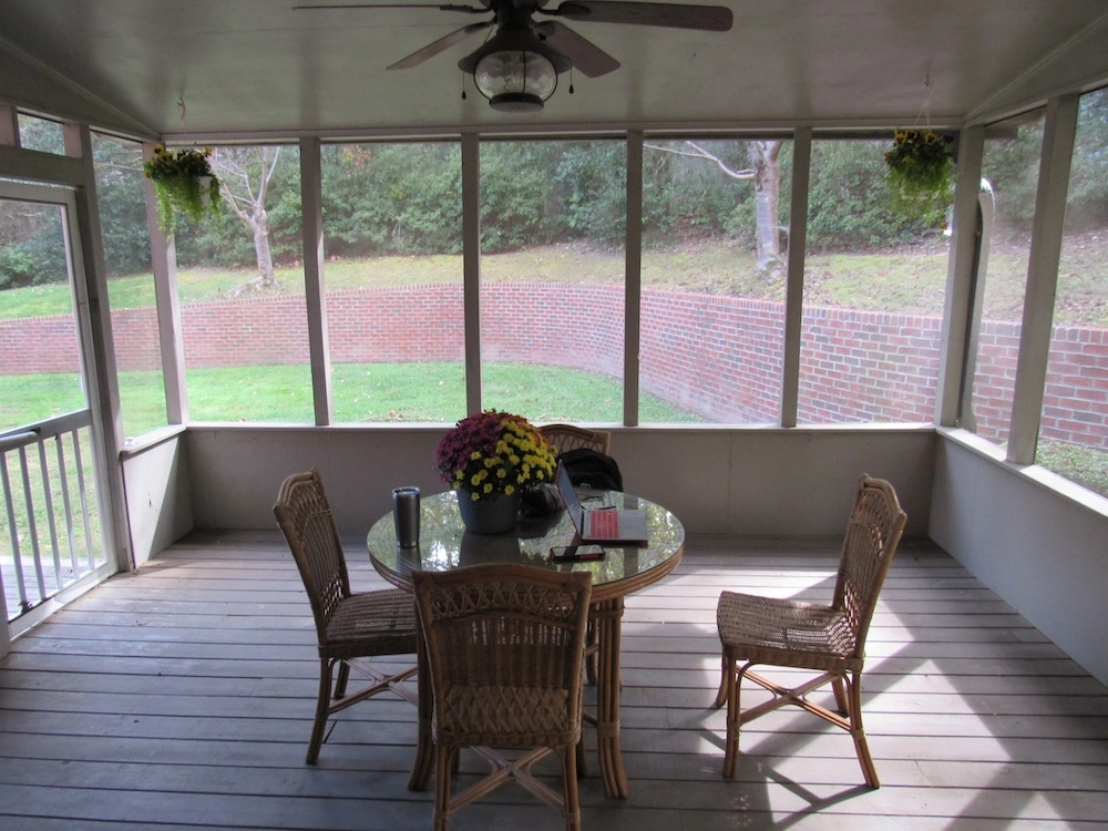 A screened-in porch with a table and chairs