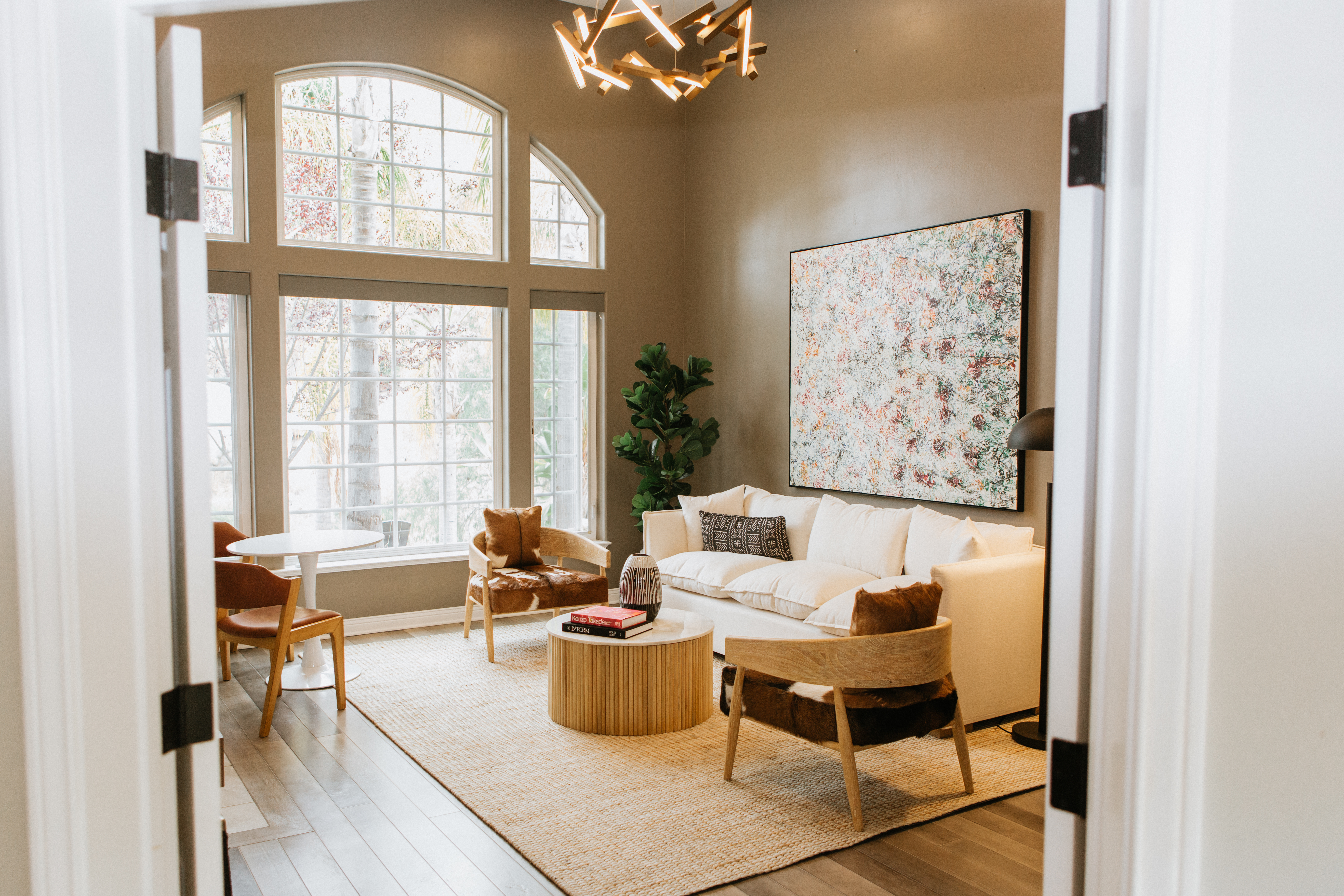 White sofa and chairs in bright lounge with large windows