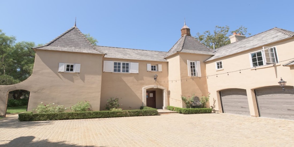 Two-story home with courtyard and garage under clear blue sky