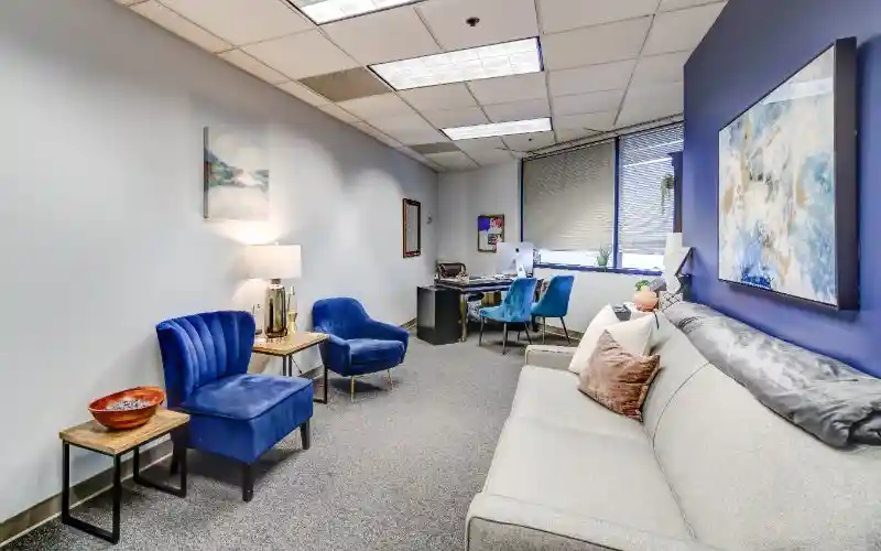 Counseling office with sofa, blue chairs, and desk workstation