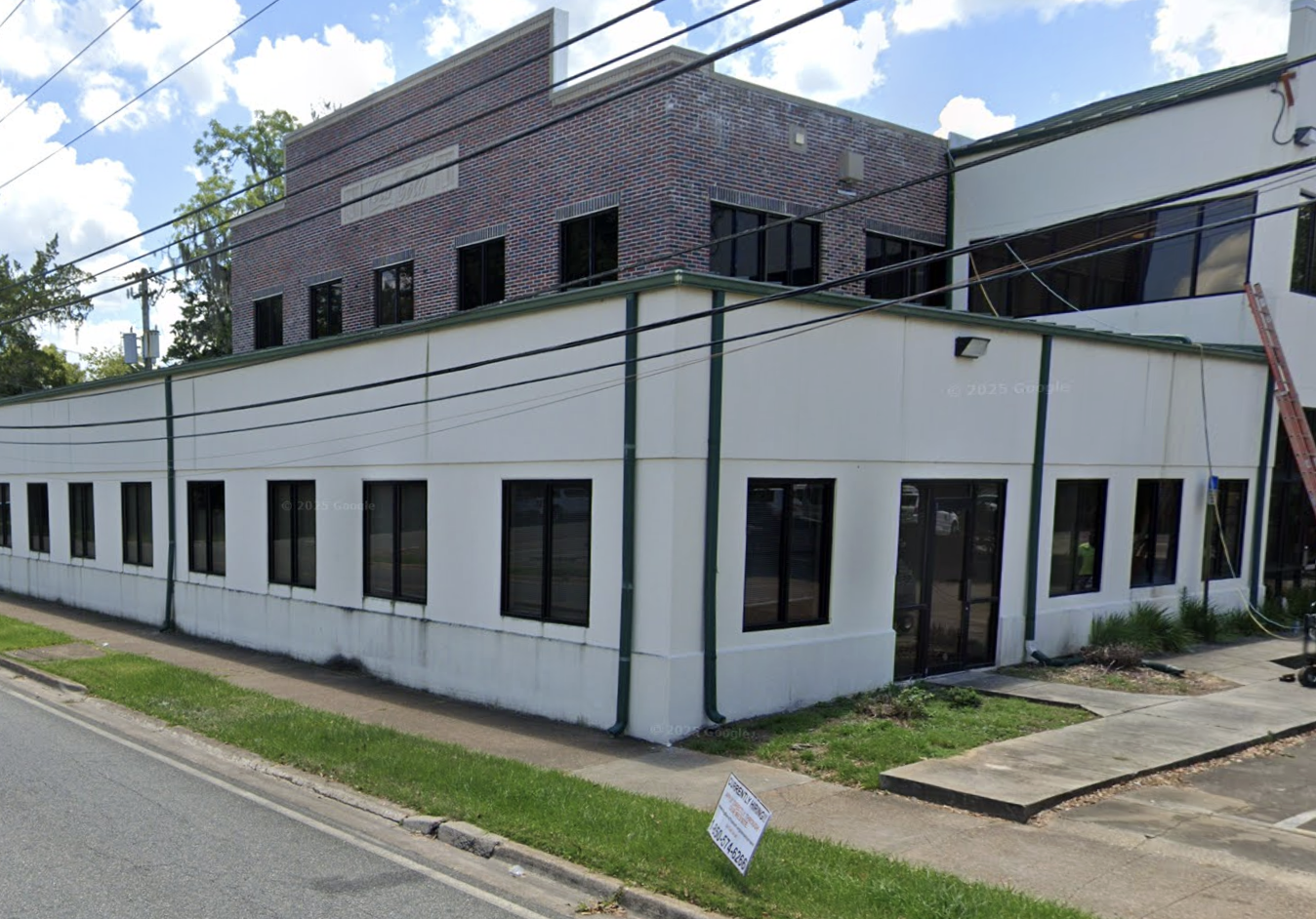 White and brick clinic building along street with rows of windows