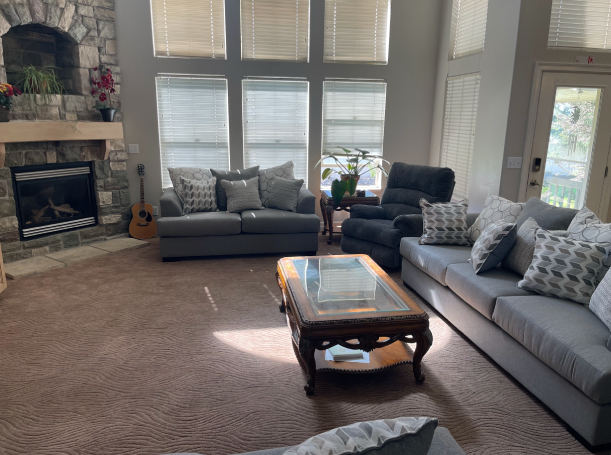 Stone fireplace with large windows and sofas