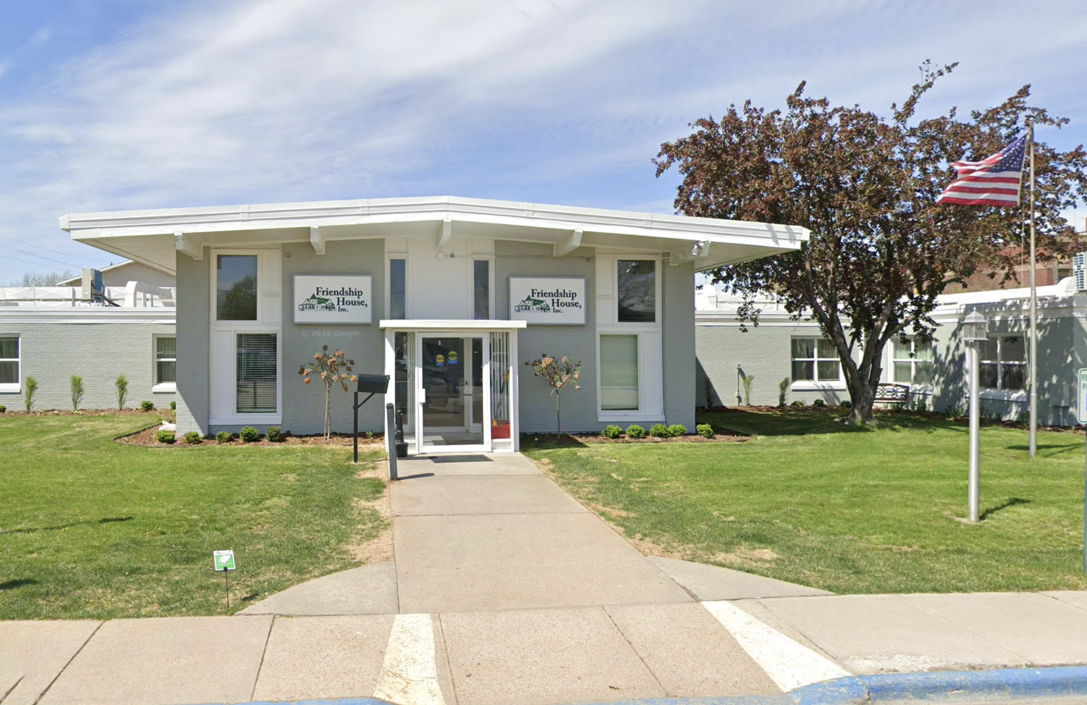 Front entrance of Friendship House with lawn and American flag