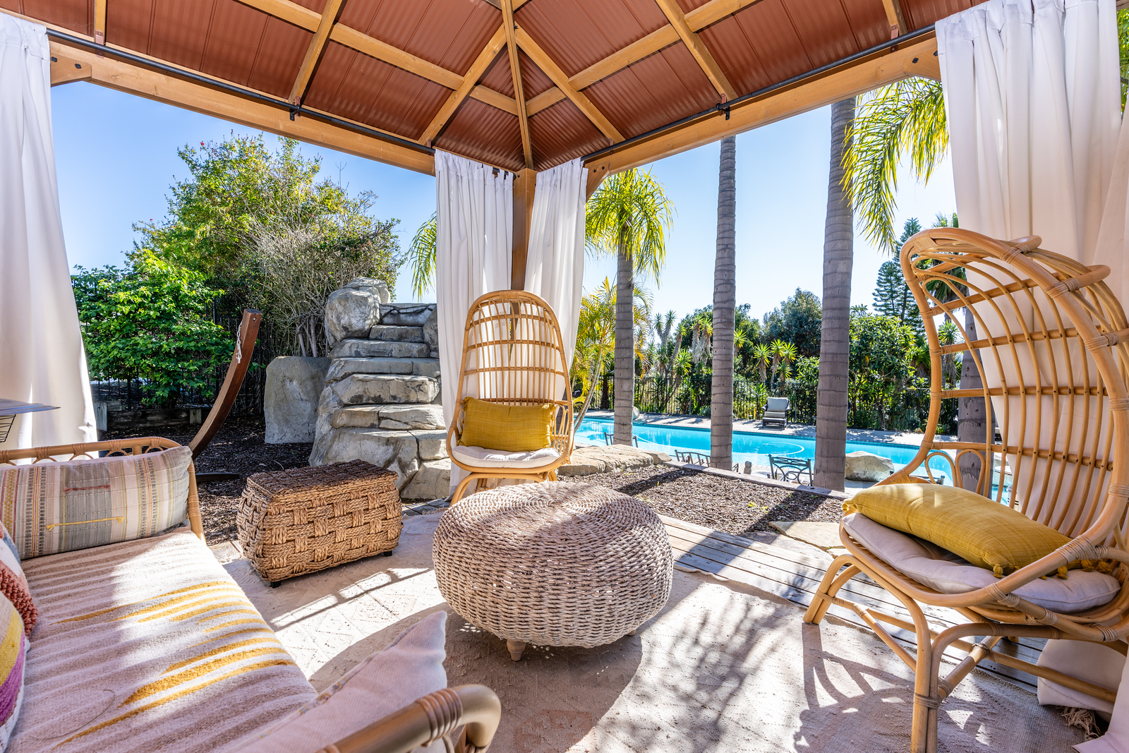 Cabana with wicker seating overlooking pool and palm trees