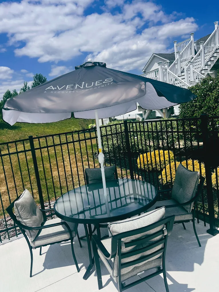 Patio table with umbrella and chairs near landscaped yard