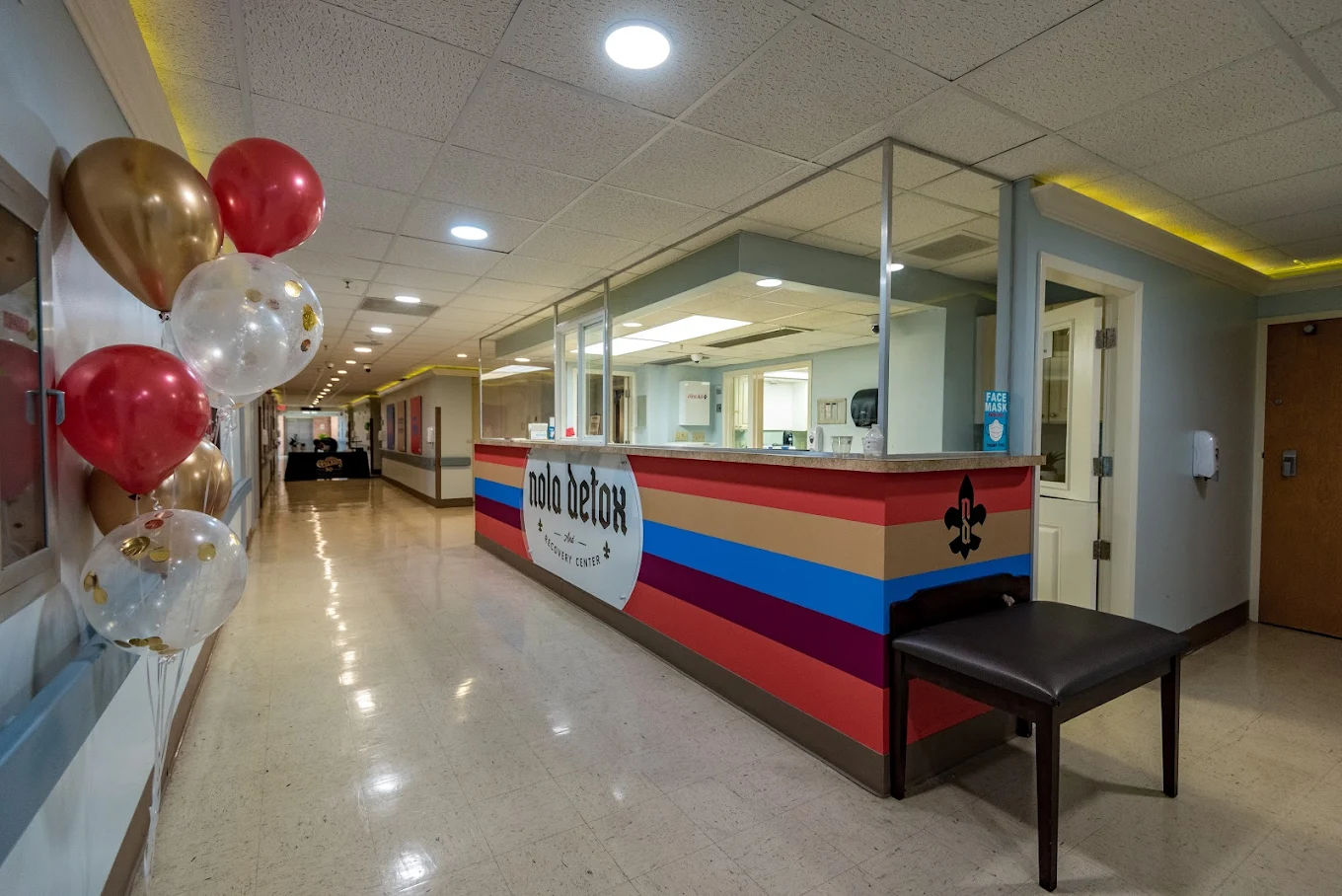 Reception desk with colorful striped design, balloons, and hallway leading to other areas of the NOLA Detox center