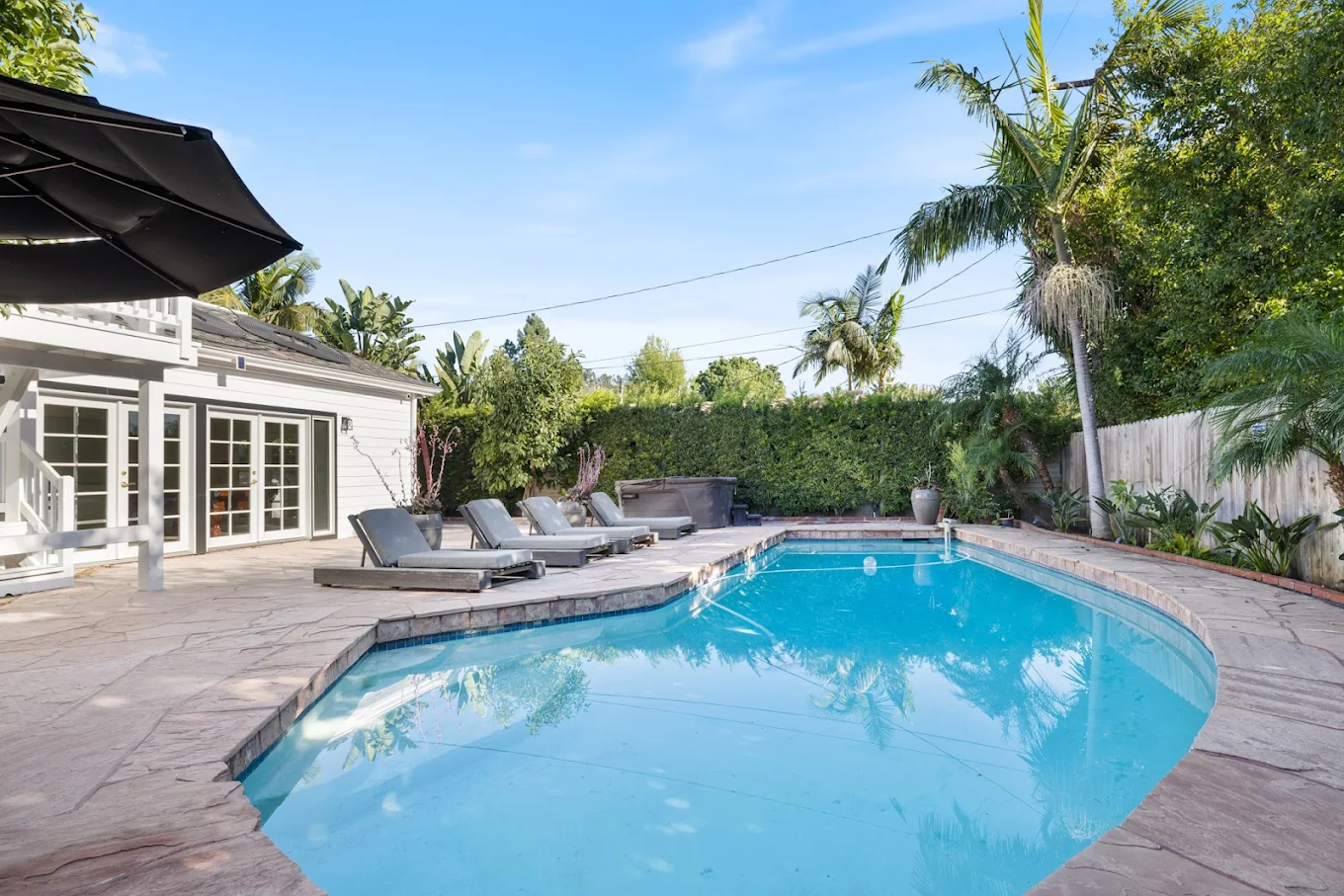 Backyard pool with lounge chairs and trees