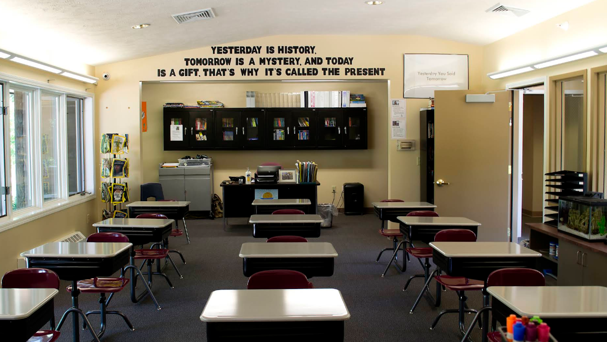 Classroom with desks, bookshelves, and quote on the wall