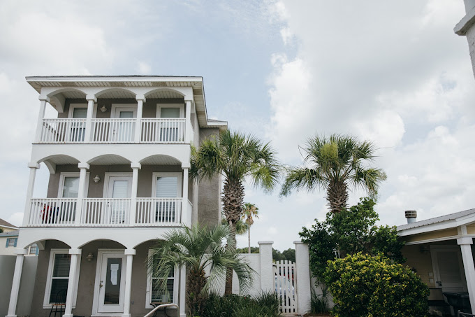 Two-story beige building with tall windows and parking lot