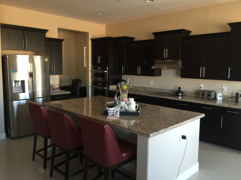 Granite kitchen island with red barstools and dark cabinets