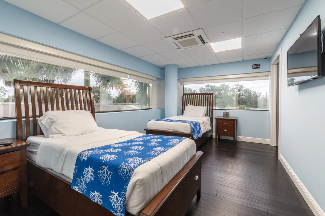 Two twin beds with blue bedding and corner windows