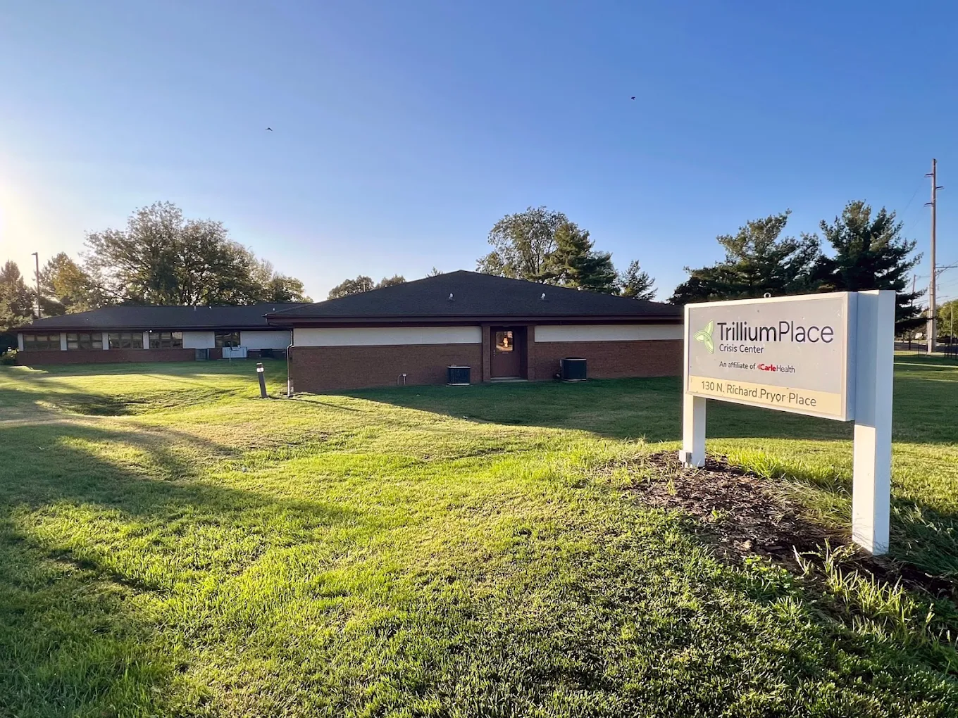 Single-story brick building with sign and open green lawn