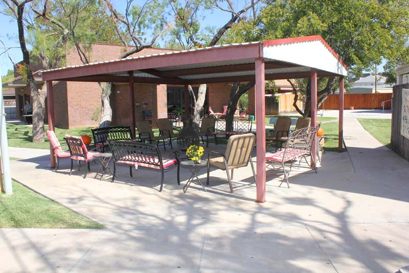 Covered outdoor area with chairs under a red metal roof