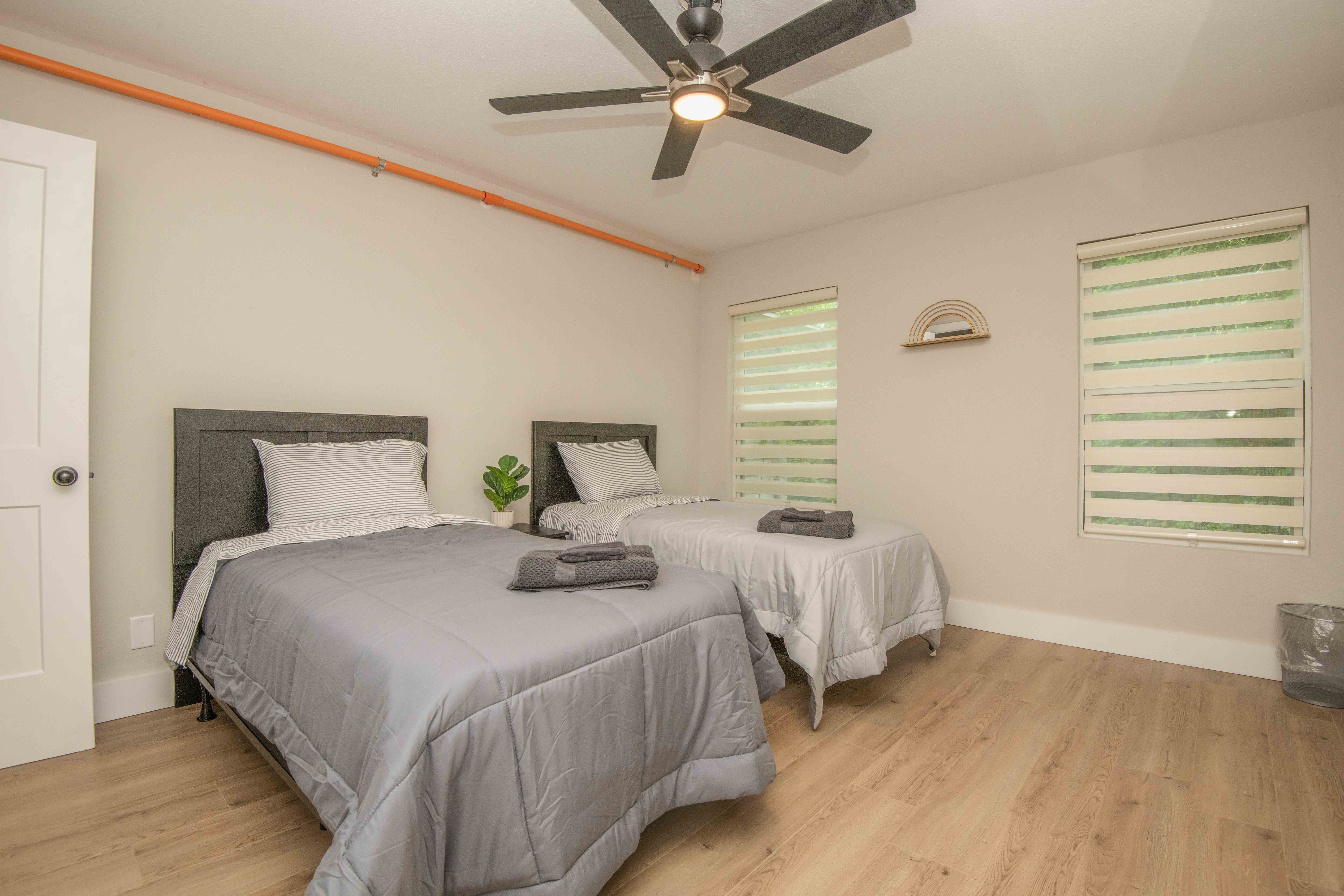Twin beds with gray comforters and large ceiling fan