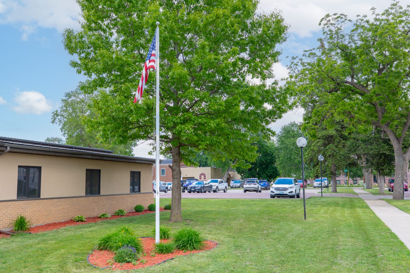 Landscaped treatment center campus with lawn, trees, flagpole, and parking area