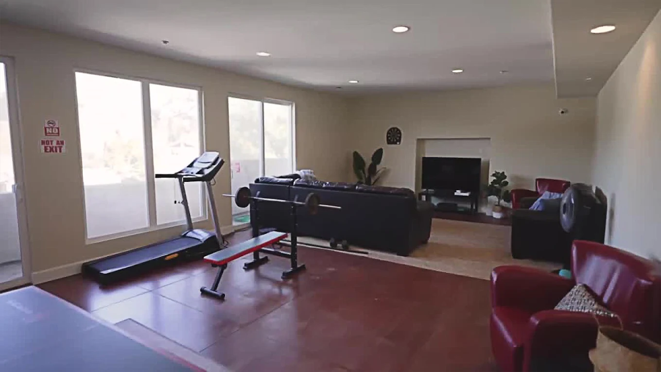 Home gym with treadmill, weights, and leather seating area