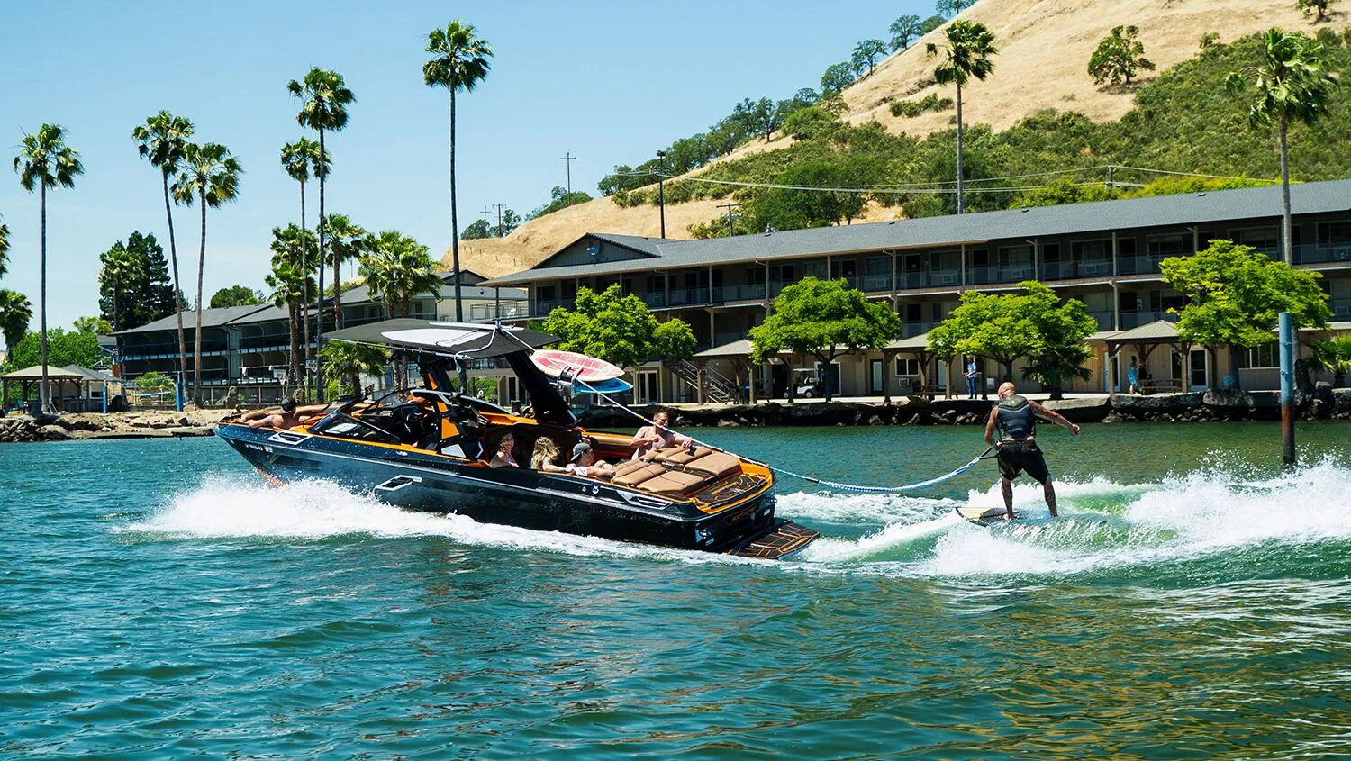 People boating and wakeboarding near lakeside treatment facility.