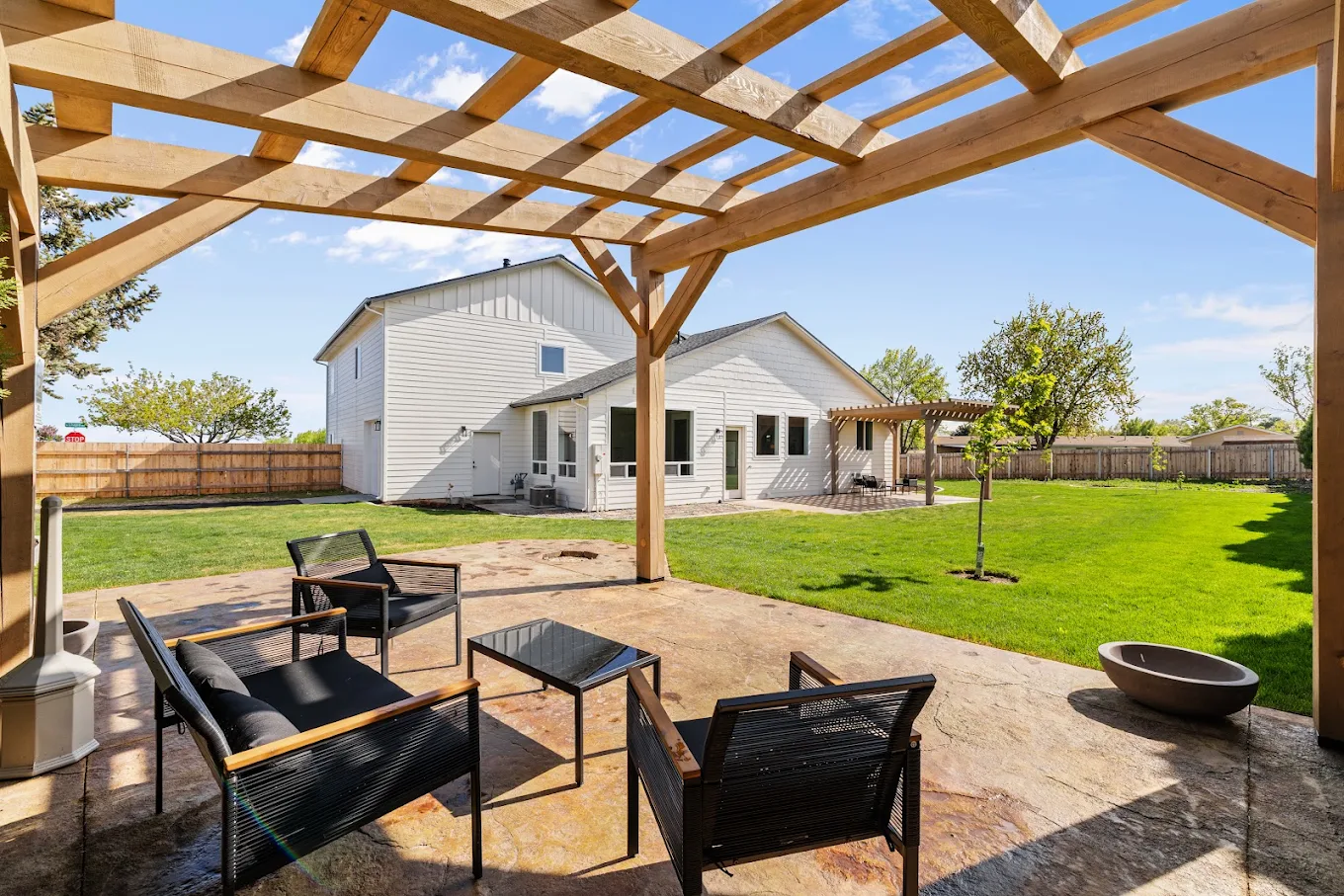 Covered patio with outdoor chairs overlooking a large lawn