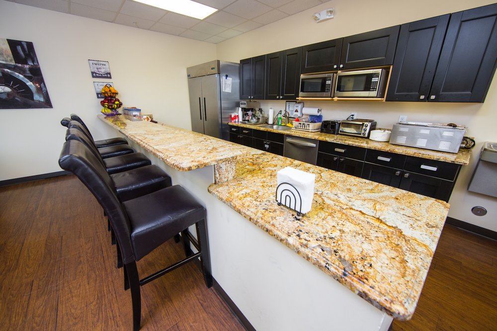 Kitchen with bar seating, black cabinets, and stainless steel appliances.