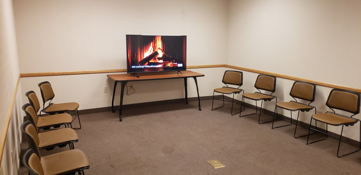 Small room with circle of chairs and TV showing fireplace