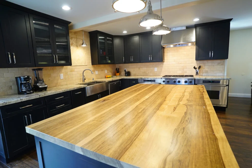 Kitchen with wooden island, black cabinets, and stainless appliances