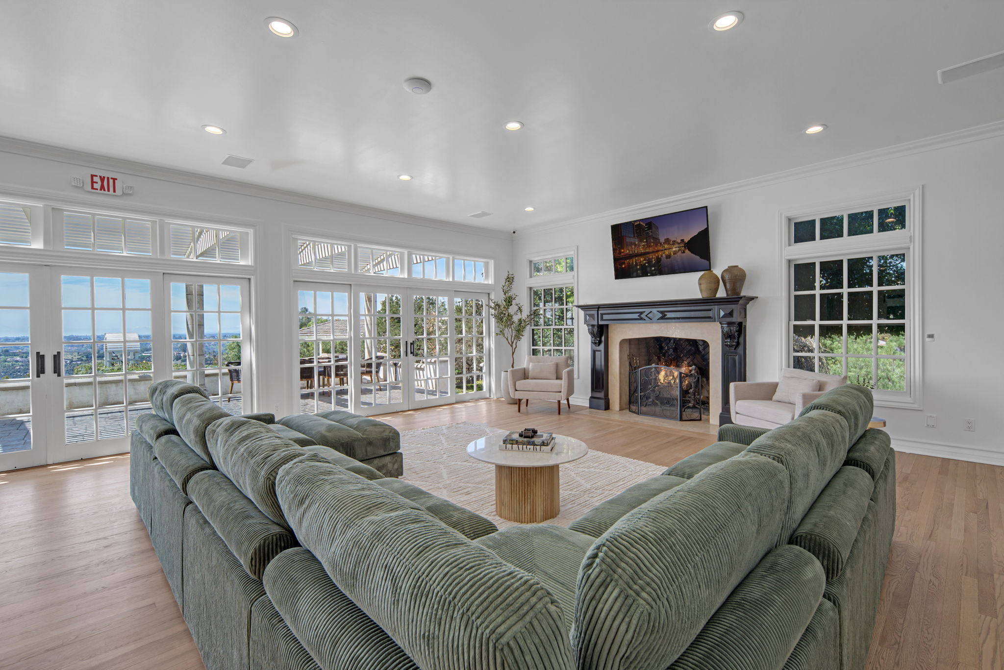 Living room with fireplace, green sofa, and large windows