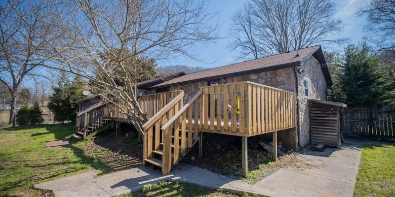 Small stone building with a wooden deck and stairs.