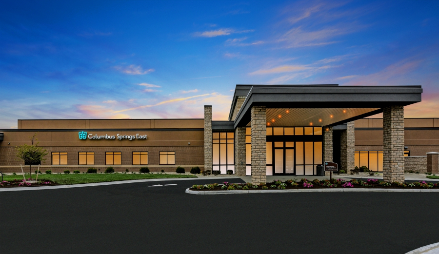 Rehab facility entrance at dusk with lit canopy and sign